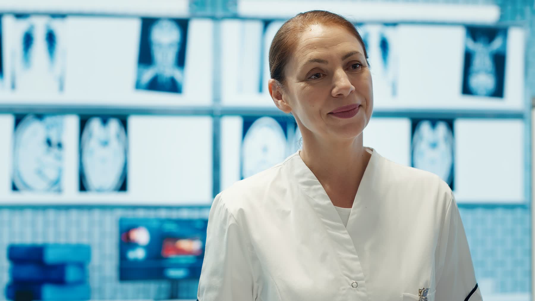 A specialist in front of a wall of radiology scans